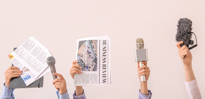 Female hands with newspapers and microphones on light background